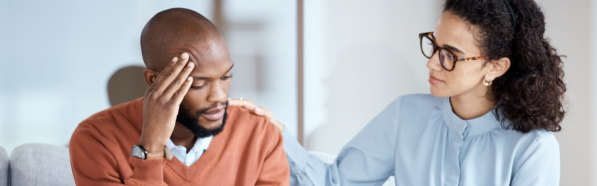 man rubbing his head with a woman comforting him